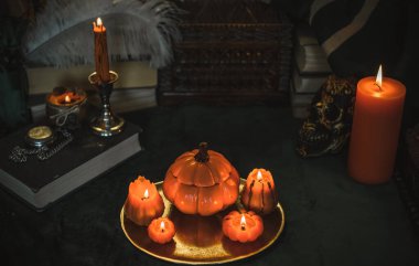 Eskimiş bir masada turuncu mum, karanlık akademi estetiği. Akşam Ekim zamanı