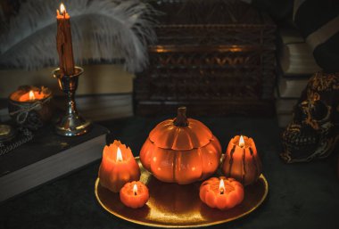 Eskimiş bir masada turuncu mum, karanlık akademi estetiği. Akşam Ekim zamanı