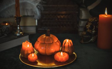 Eskimiş bir masada turuncu mum, karanlık akademi estetiği. Akşam Ekim zamanı