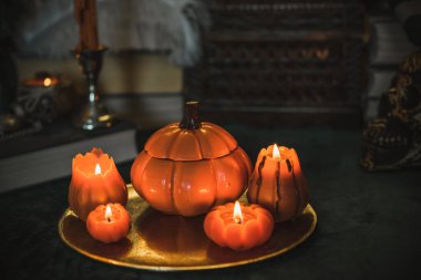 Eskimiş bir masada turuncu mum, karanlık akademi estetiği. Akşam Ekim zamanı