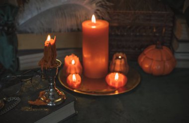 Eskimiş bir masada turuncu mum, karanlık akademi estetiği. Akşam Ekim zamanı