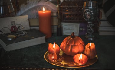 Eskimiş bir masada turuncu mum, karanlık akademi estetiği. Akşam Ekim zamanı