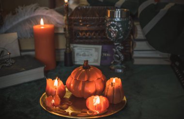 Eskimiş bir masada turuncu mum, karanlık akademi estetiği. Akşam Ekim zamanı