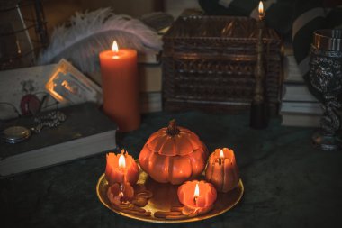 Eskimiş bir masada turuncu mum, karanlık akademi estetiği. Akşam Ekim zamanı