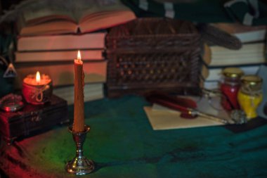 Eskimiş bir masada turuncu mum, karanlık akademi estetiği. Akşam Ekim zamanı