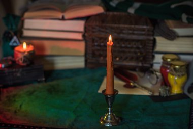 Eskimiş bir masada turuncu mum, karanlık akademi estetiği. Akşam Ekim zamanı