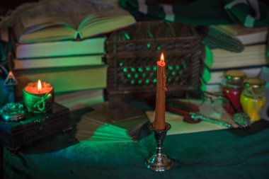 Eskimiş bir masada turuncu mum, karanlık akademi estetiği. Akşam Ekim zamanı