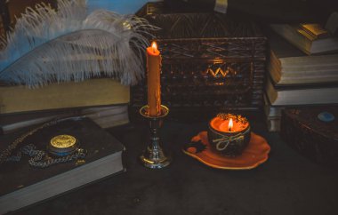 Eskimiş bir masada turuncu mum, karanlık akademi estetiği. Akşam Ekim zamanı