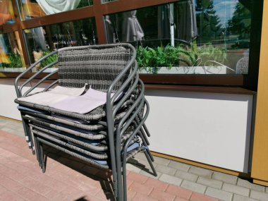 Güneşli bir yaz gününde bir sokak kafesinin terasında bir yığın sandalye. Sezon kapanıyor..