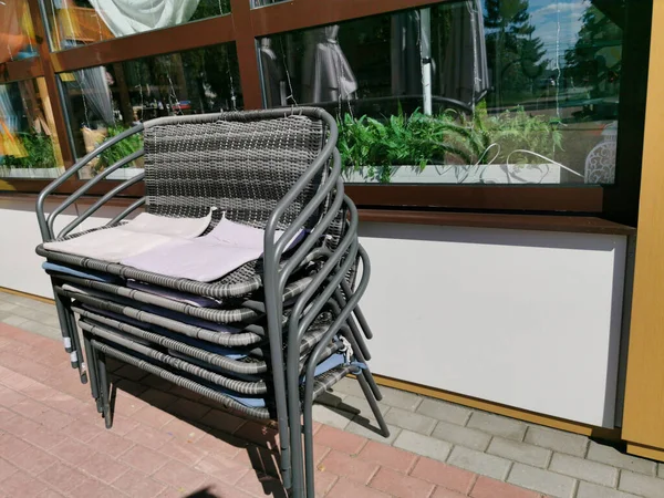 Montón de sillas en la terraza de verano de un café de la calle en un día soleado de verano. Cerrar la temporada. — Foto de Stock