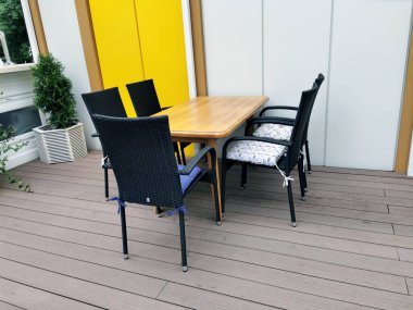 Boş bir kafeterya terası. Güneşli bir günde, şehir parkında, tente altında çiçekler olan masa ve sandalyeler..