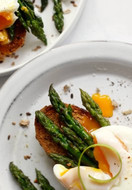 Kahvaltı için haşlanmış yumurta ve ekmek ile kaplanmış yeşil kuşkonmaz.