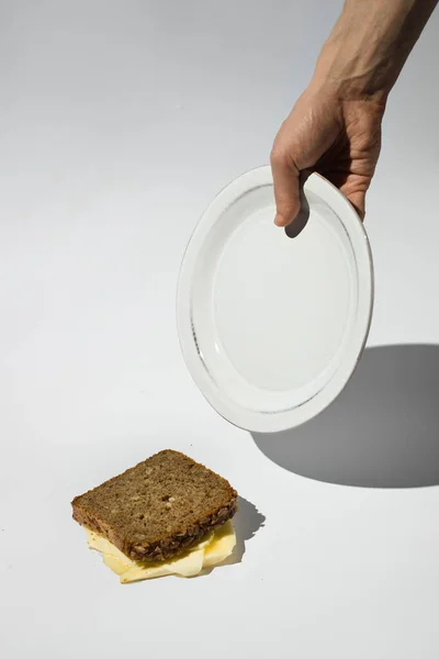 fallen bread peace with butter food waste from a plate on the floor. hand holding a plate. Conceptual picture