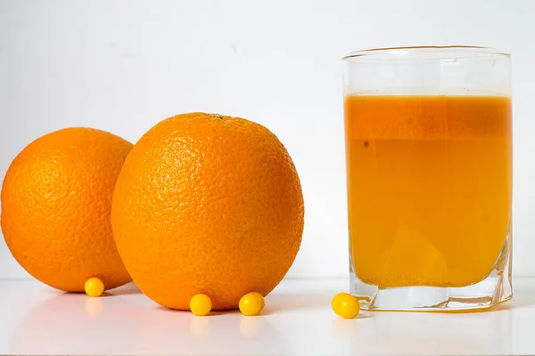 orange on a white background with vitamins and a glass of juice