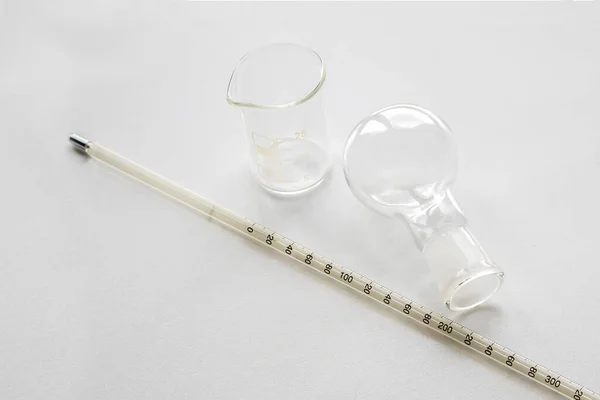 Round bottom flask, beaker and thermometer for chemistry laboratory isolated on white background. Laboratory glassware round bottom flask, beaker and thermometer with concept of science.