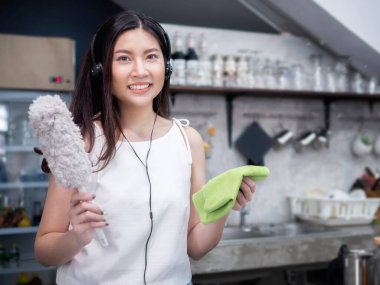 Genç ve mutlu Asyalı ev hanımı evde ya da kahvesinde temizlik yaparken eğleniyor.