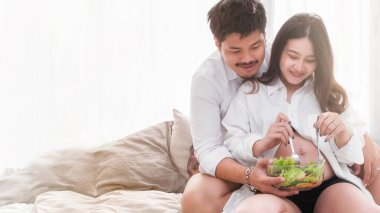Hamilelik sağlıklı yiyecekler ve insanlar hamile. Müstakbel anne ve baba sağlıklı salata yiyor ve birlikte bakıyorlar..