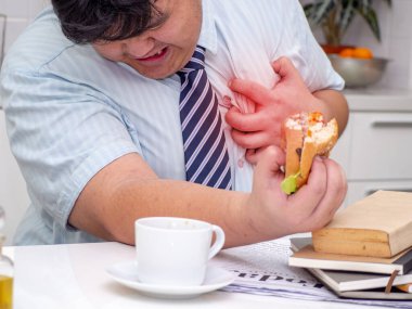 Fat Asian man felling heart pain while he eating food.Man with chest pain suffering from heart attack. clipart