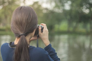 Modern bahçe parkında geçmişe dönük kameralı oldukça havalı bir Asyalı kadın ya da aynasız bir kamera.