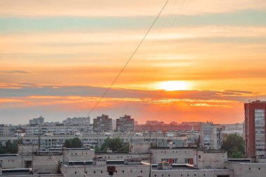 Şehir evlerinin üzerinde kırmızı gün batımı ve mavi gökyüzü