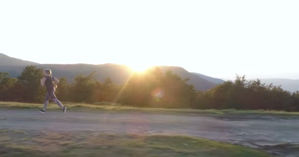 Mujer corriendo en una carretera de campo al atardecer . — Vídeo de stock