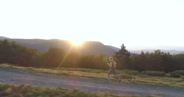 Kvinnan kör på landsbygden väg vid solnedgången. — Stockvideo