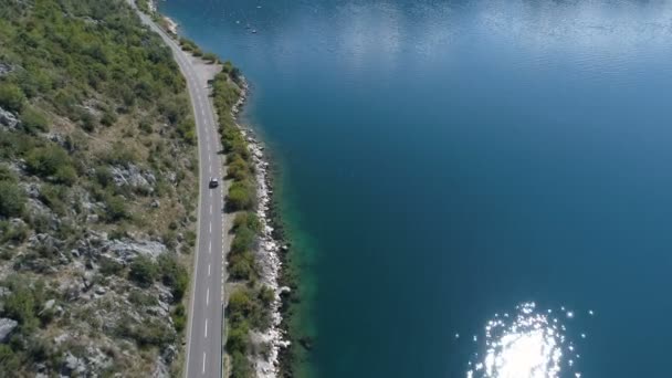 岩の多い海岸の上の海岸沿い道路に沿って運転している車 — ストック動画