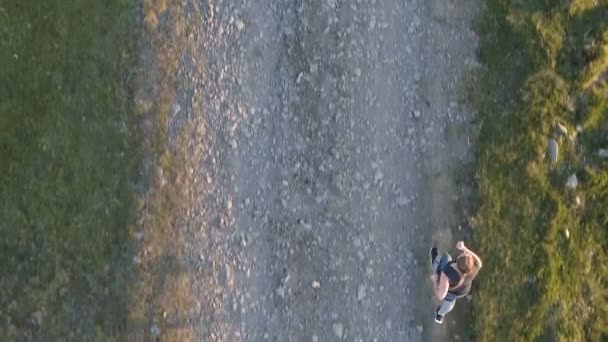 Mujer corriendo en una carretera de campo al atardecer . — Vídeos de Stock