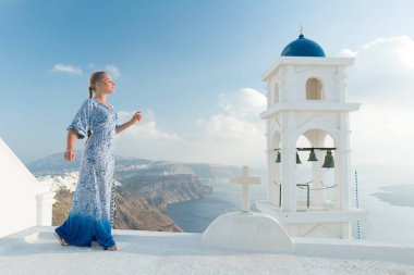 Santorini, Yunanistan onun tatil zevk beyaz ve mavi elbiseli mutlu kadın. Caldera ve Ege Denizi üzerinden Imerovigli görüntüleyin.