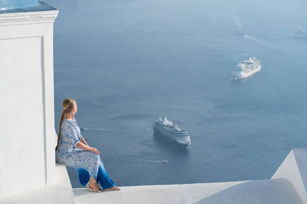 Mujer feliz en vestido blanco y azul disfrutando de sus vacaciones en Santorini, Grecia. Vista sobre la Caldera y el mar Egeo desde Imerovigli . — Foto de Stock