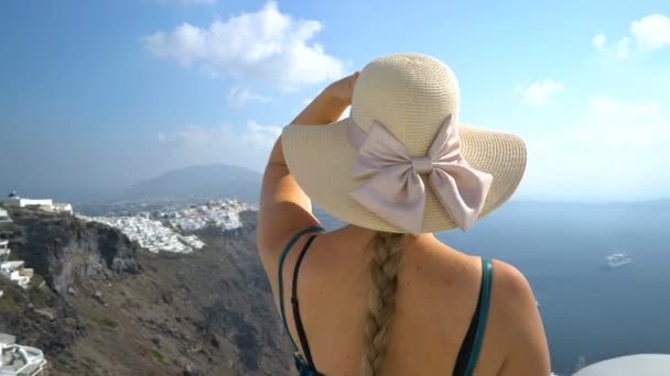 Mujer feliz en vestido verde y sombrero de sol disfrutando de sus vacaciones en Santorini, Grecia. Vista sobre la Caldera y el mar Egeo desde Imerovigli . — Vídeo de stock