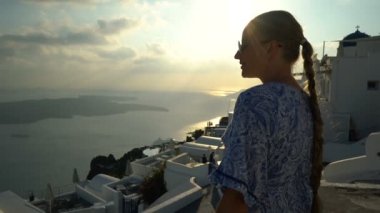 Santorini, Yunanistan onun tatil zevk beyaz ve mavi elbiseli mutlu kadın. Caldera ve Ege Denizi üzerinden Imerovigli görüntüleyin. Etkin, seyahat, turizm kavramları