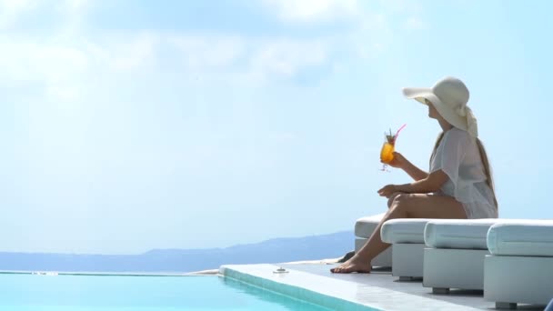 Young woman drinking a cocktail enjoying a magnificent view of Santorini near the pool — Stock Video