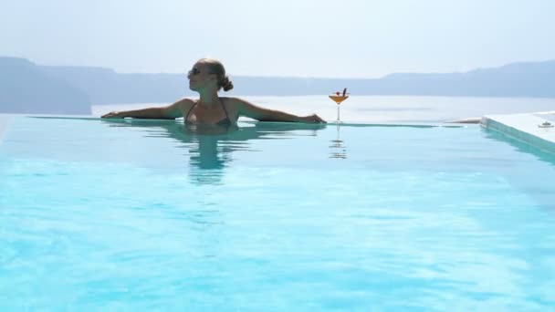 Mujer joven relajándose en la piscina con una hermosa vista en Santorini — Vídeos de Stock