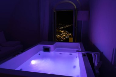 Lüks seyahat Santorini tatil otel Jakuzi şehrin gece manzaralı renkli ışıklar ve.