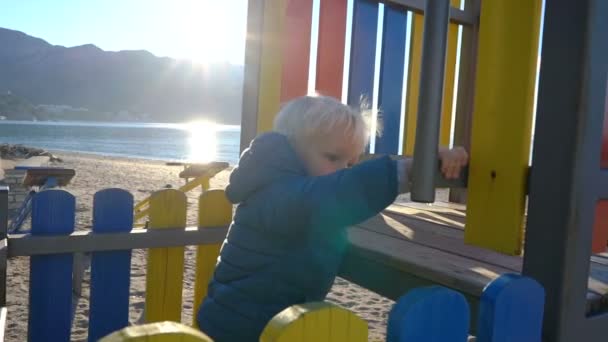 Unterwegs klettert ein kleiner Junge die Rutsche hinauf, bemerkt einen in der Sonne glitzernden Wassertropfen und wundert sich darüber — Stockvideo