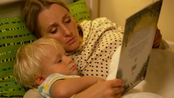 Mère et bébé fils lisant un livre au lit — Video