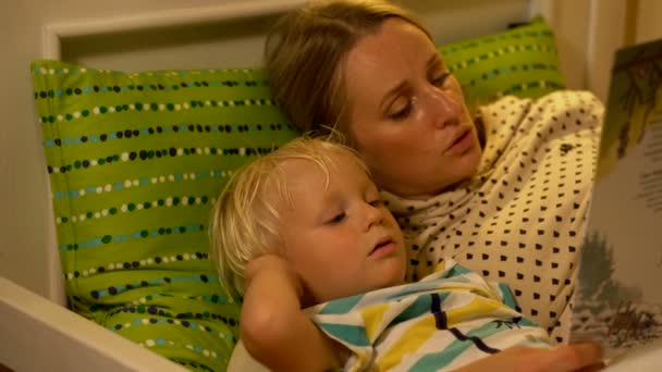 Mor och baby son en bok i sängen — Stockvideo