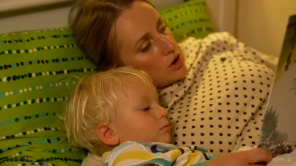 Mor och baby son en bok i sängen — Stockvideo