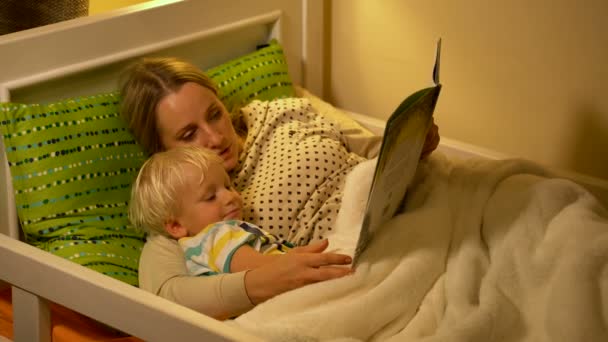 Madre e hijo bebé leyendo un libro en la cama — Vídeos de Stock