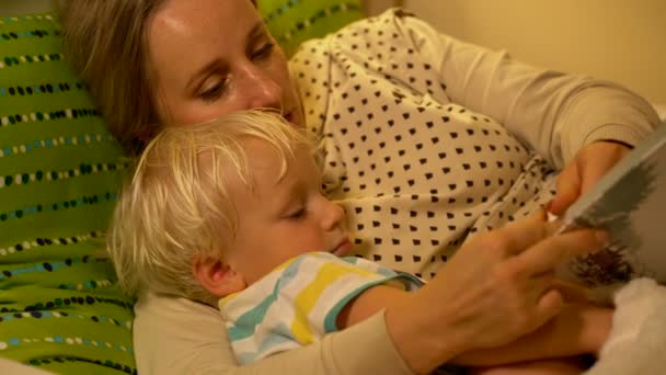 Mor och baby son en bok i sängen — Stockvideo