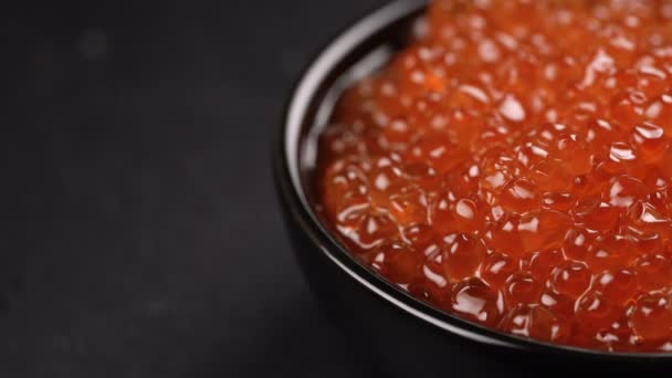 Caviar rojo girado sobre fondo negro . — Vídeo de stock