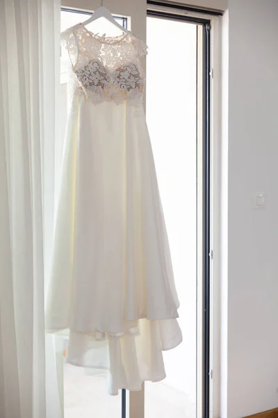 Wedding dress hanging on a hanger against the window — Stock Photo, Image