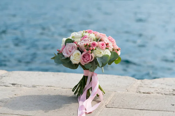 Růžová bílá svatební kytice stojí na molu u moře — Stock fotografie