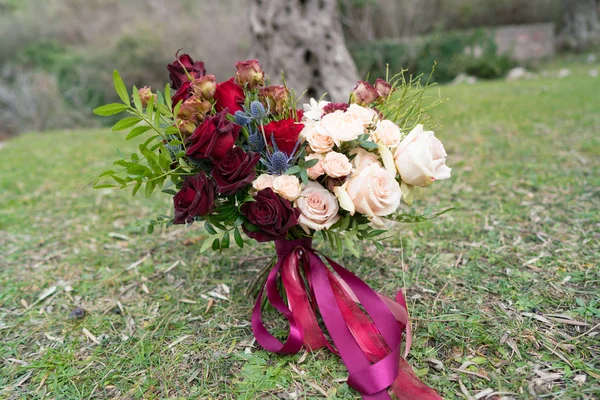 Red-pink wedding bouquet of roses standing on the grass — Stock Photo, Image