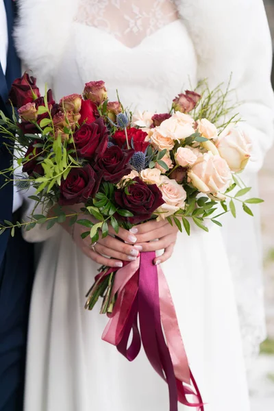 Red-pink wedding bouquet of roses and greenery in the hands of the bride — Stock Photo, Image