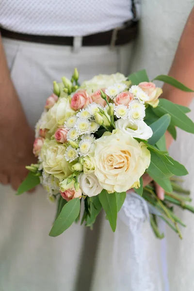 De bruid houdt een boeket roze en beige bruiloft van verse bloemen en eucalyptus — Stockfoto