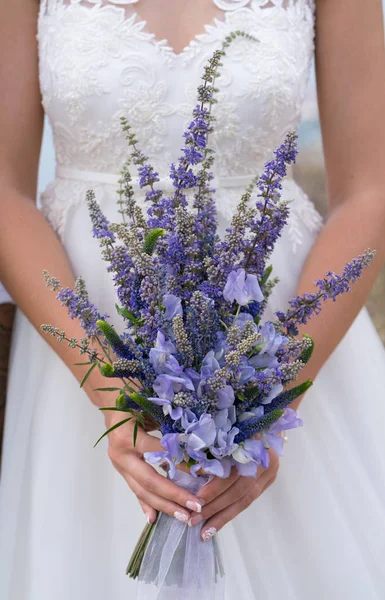 Novia sostiene elegante ramo de flores y hierbas moradas — Foto de Stock