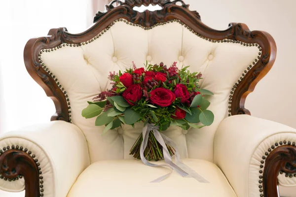 Bouquet da sposa rosso brillante di fiori freschi ed eucalipto si erge sulla poltrona — Foto Stock
