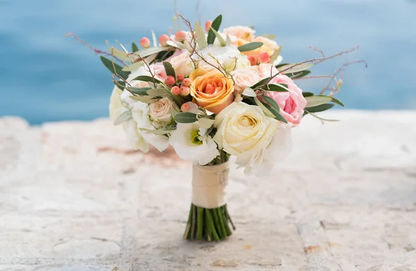 A rounded wedding bouquet stands on the pier against the background of the sea — Stock Photo, Image